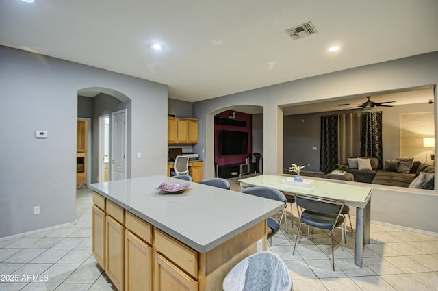 kitchen with light tile patterned flooring, a center island, and ceiling fan