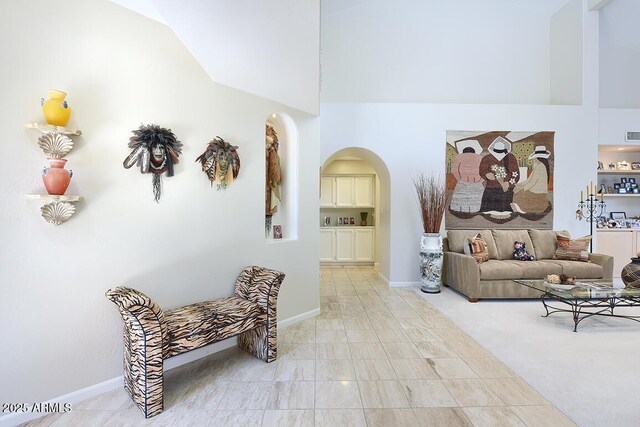 10068 E Cinnabar Ave, Scottsdale, AZ 85258 - living area with baseboards, a high ceiling, arched walkways, and light colored carpet