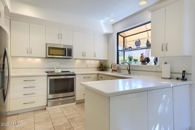 10068 E Cinnabar Ave, Scottsdale, AZ 85258 - kitchen with decorative backsplash, light countertops, a peninsula, appliances with stainless steel finishes, and white cabinetry