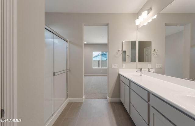 full bathroom with double vanity, a shower stall, a sink, and tile patterned floors