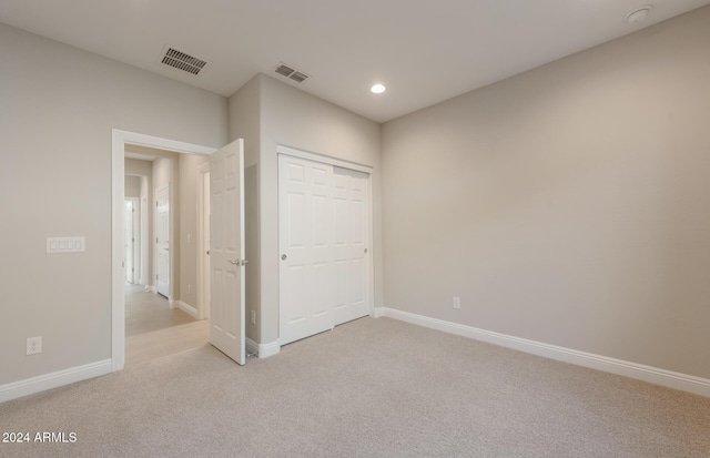 unfurnished bedroom featuring light carpet and a closet