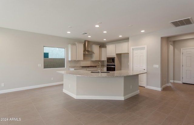 kitchen with stainless steel appliances, visible vents, a sink, and wall chimney exhaust hood