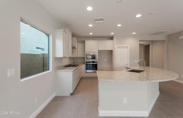 kitchen with visible vents, appliances with stainless steel finishes, light tile patterned flooring, a sink, and light stone countertops