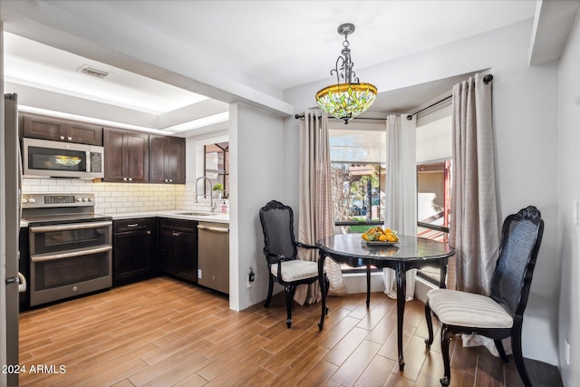 kitchen featuring dark brown cabinetry, sink, stainless steel appliances, light hardwood / wood-style floors, and decorative light fixtures