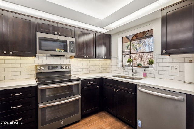 kitchen with backsplash, sink, light hardwood / wood-style flooring, appliances with stainless steel finishes, and dark brown cabinets