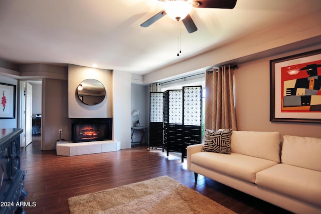 living room featuring dark hardwood / wood-style floors, ceiling fan, and a tile fireplace