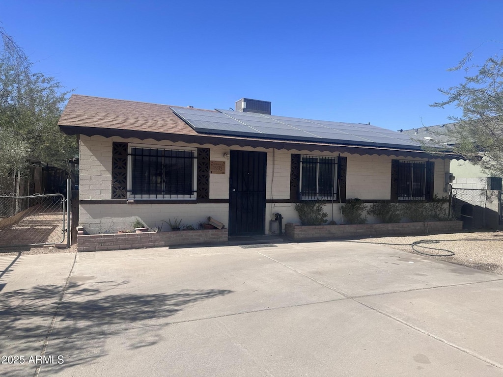 view of front of home featuring a shingled roof, a gate, fence, and solar panels