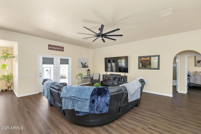 living room featuring dark wood-style floors, visible vents, arched walkways, and a ceiling fan