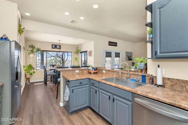 kitchen featuring stainless steel appliances, recessed lighting, a sink, blue cabinets, and light wood-type flooring