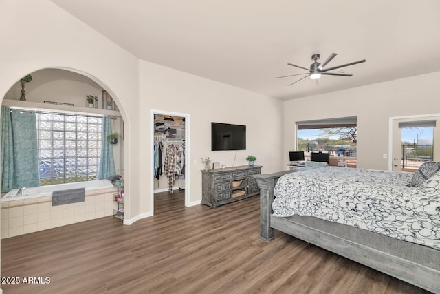 bedroom featuring a spacious closet, ceiling fan, wood finished floors, access to outside, and baseboards