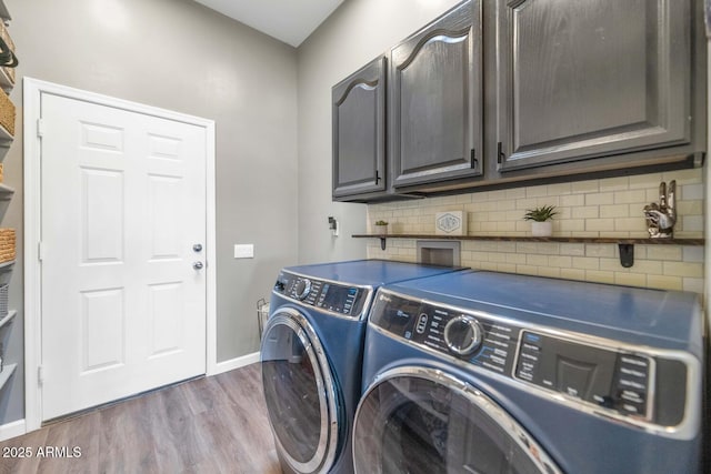 laundry area with baseboards, wood finished floors, cabinet space, and washer and dryer