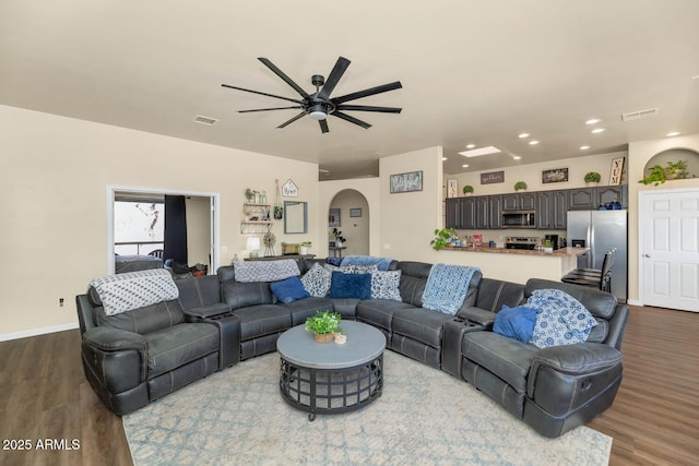 living room with visible vents, arched walkways, and dark wood-style flooring