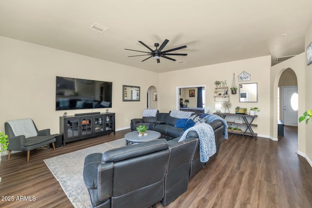 living area with a ceiling fan, arched walkways, baseboards, and wood finished floors