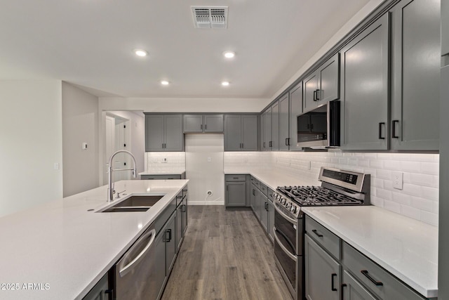 kitchen featuring sink, stainless steel appliances, gray cabinets, and hardwood / wood-style flooring