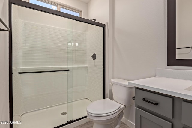 bathroom with toilet, an enclosed shower, and vanity