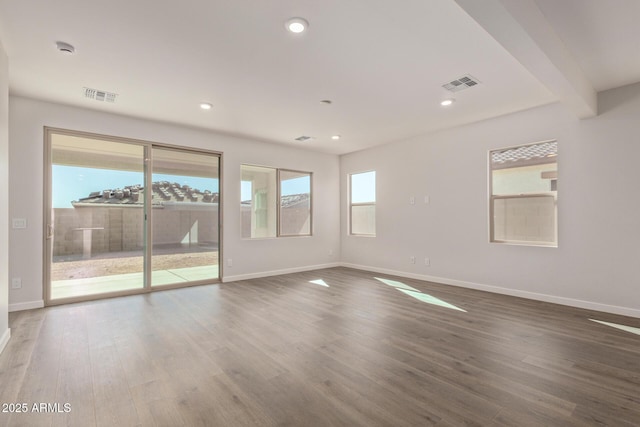 empty room with beam ceiling and hardwood / wood-style flooring