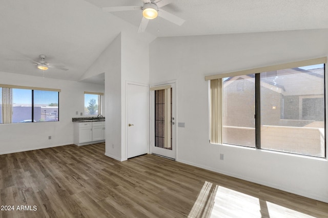 unfurnished living room with dark wood-type flooring, high vaulted ceiling, and ceiling fan