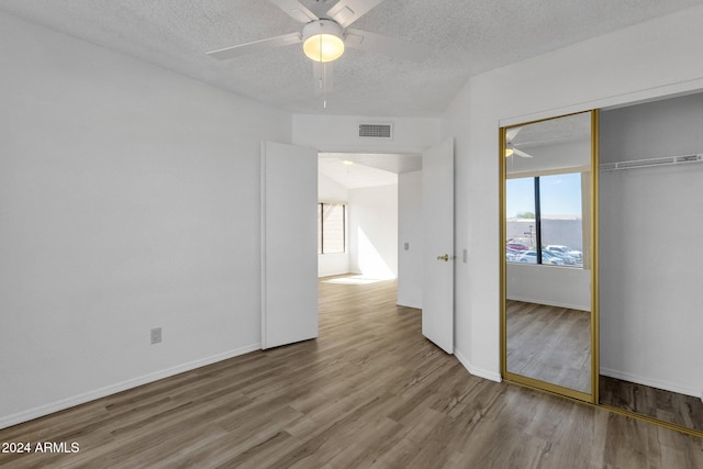 unfurnished bedroom with a closet, ceiling fan, a textured ceiling, and hardwood / wood-style floors