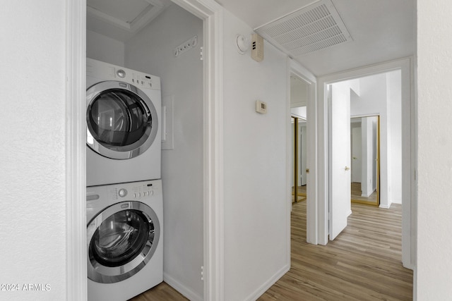 clothes washing area with stacked washer / drying machine and wood-type flooring