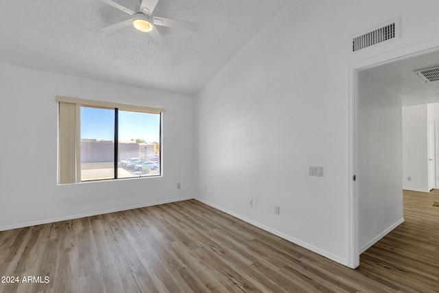 unfurnished room featuring hardwood / wood-style floors, vaulted ceiling, a textured ceiling, and ceiling fan