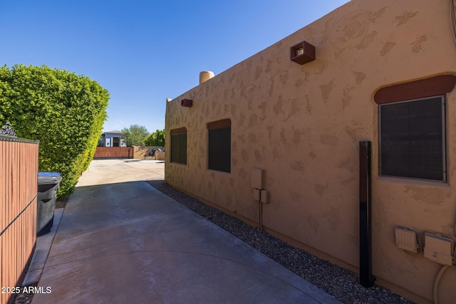 view of side of home featuring a patio, fence, and stucco siding