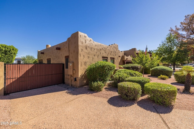 view of side of property featuring a gate and stucco siding