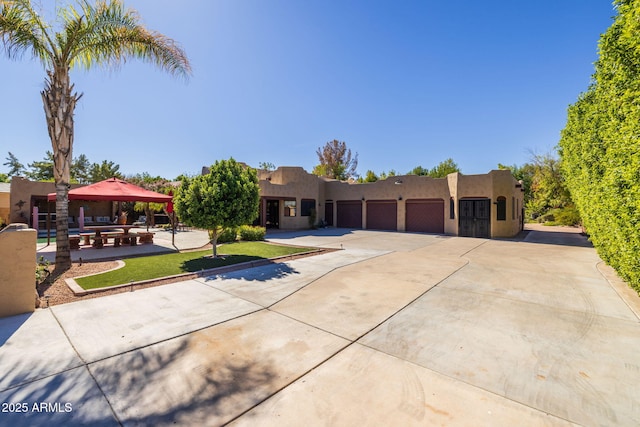 pueblo-style home featuring a gazebo, a garage, driveway, and stucco siding