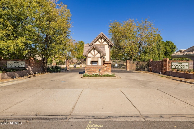 tudor house featuring brick siding, fence, a gate, and stucco siding