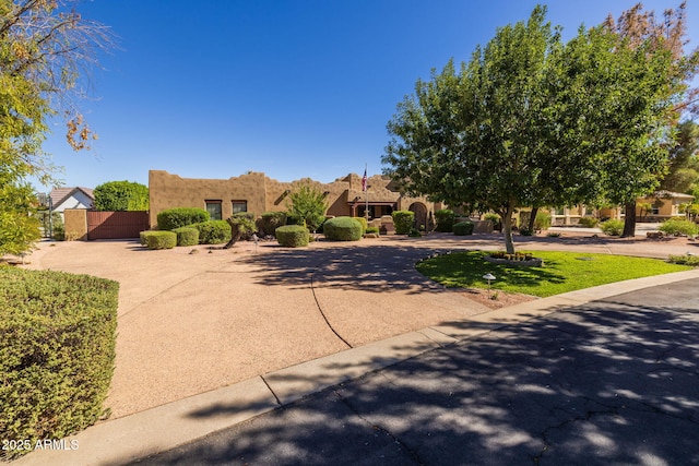 pueblo revival-style home with a gate and stucco siding