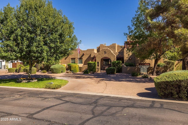 pueblo-style home featuring curved driveway, stucco siding, and a residential view