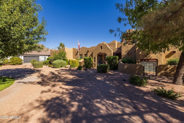 pueblo-style house featuring a gate and stucco siding