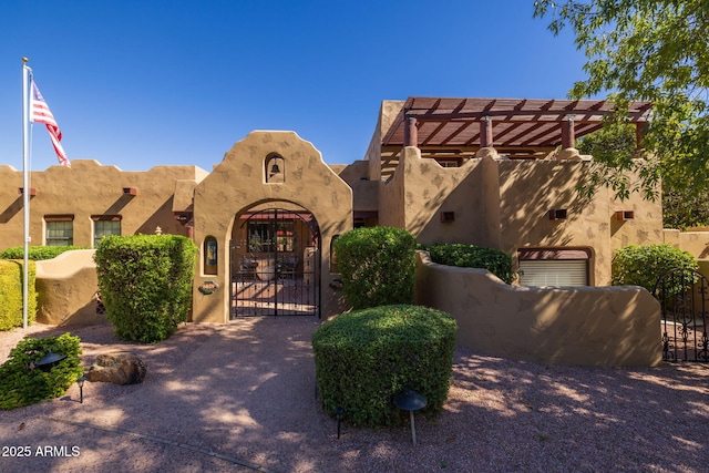 pueblo revival-style home featuring fence and a gate