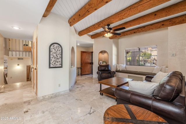 living area featuring baseboards, arched walkways, ceiling fan, and beam ceiling