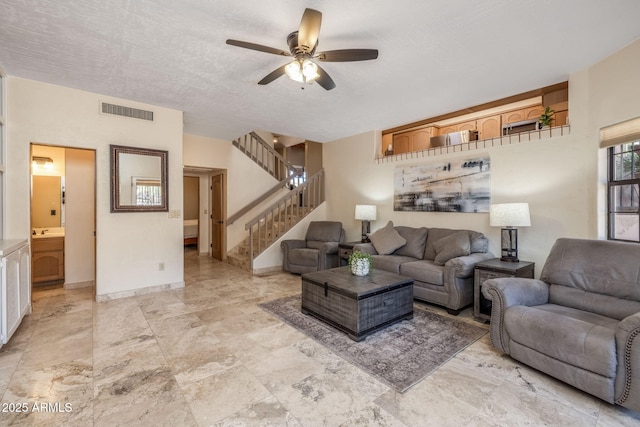 living room with ceiling fan, stairs, and visible vents