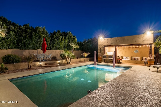 pool at night featuring a patio, a fenced in pool, fence, and outdoor dining area