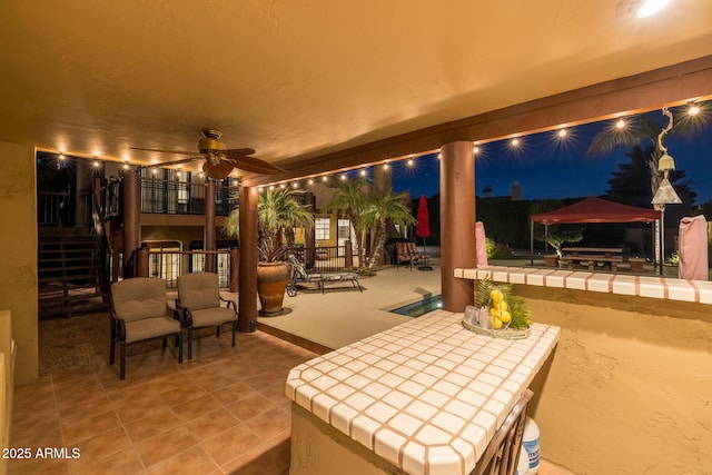 patio at night featuring stairway and a ceiling fan