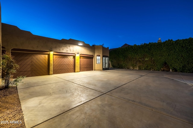 exterior space with a garage, stucco siding, and concrete driveway
