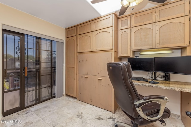 office area featuring built in study area, stone finish floor, and ceiling fan
