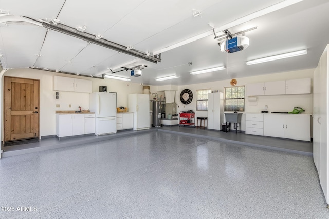 garage with freestanding refrigerator, water heater, and a garage door opener