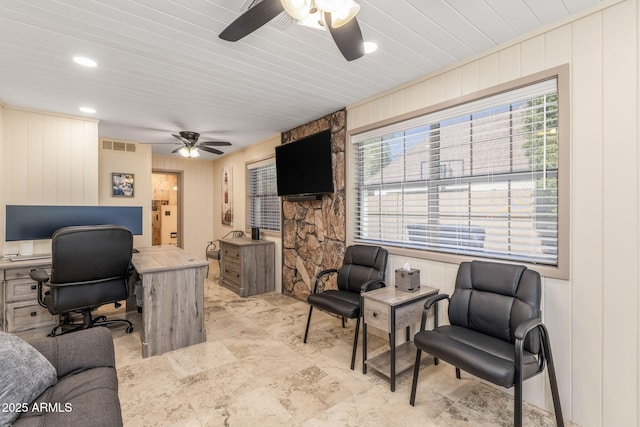office space with a ceiling fan, wood walls, visible vents, and a decorative wall