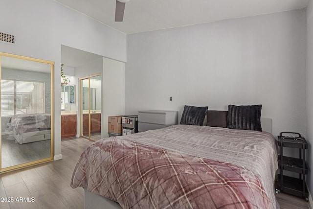 bedroom featuring a ceiling fan, visible vents, and wood finished floors