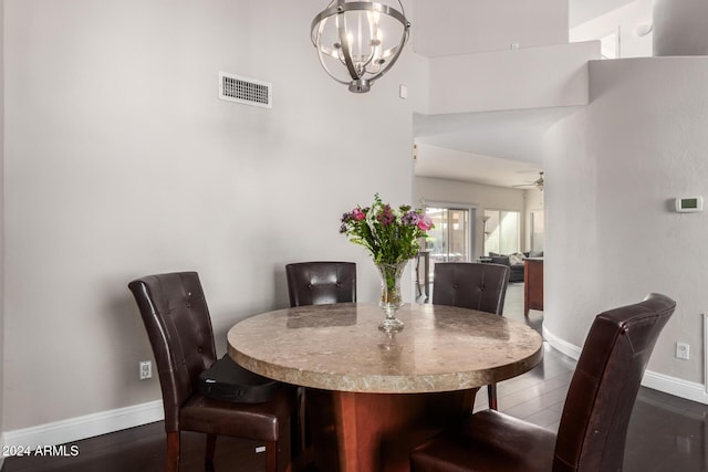 dining room with ceiling fan with notable chandelier, a towering ceiling, and dark hardwood / wood-style flooring