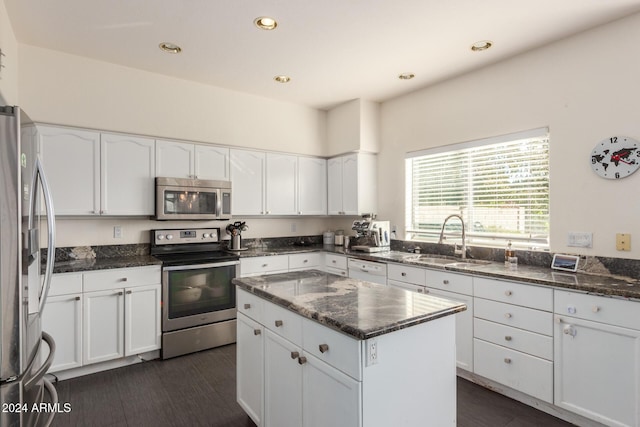 kitchen featuring white cabinets, stainless steel appliances, dark stone counters, and sink