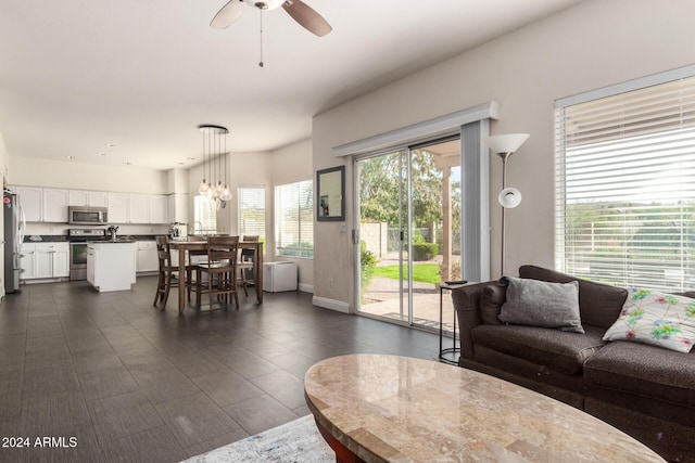 living room featuring ceiling fan with notable chandelier, a healthy amount of sunlight, and sink