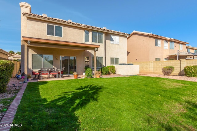 back of house featuring a lawn and a patio