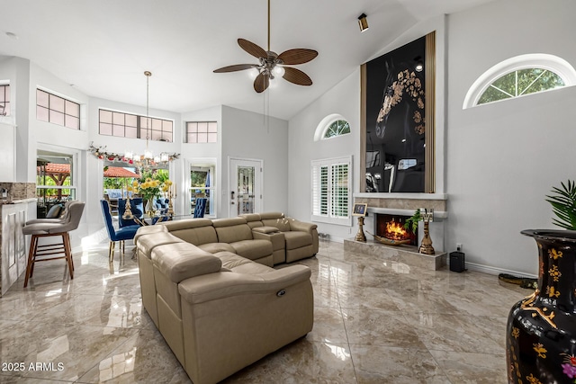 6941 W Voltaire Ave, Peoria, AZ 85381 - living area with marble tiled flooring, high vaulted ceiling, a lit fireplace, a ceiling fan, and a chandelier