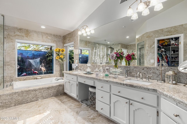 6941 W Voltaire Ave, Peoria, AZ 85381 - full bathroom with double vanity, a bath, a spacious closet, tile walls, and high vaulted ceiling