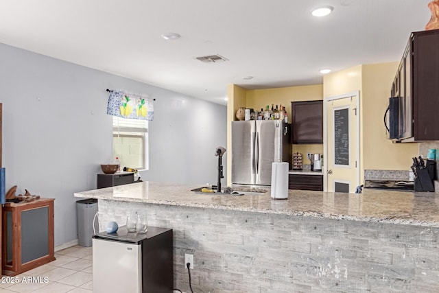 kitchen with light tile patterned floors, black appliances, light stone counters, and visible vents