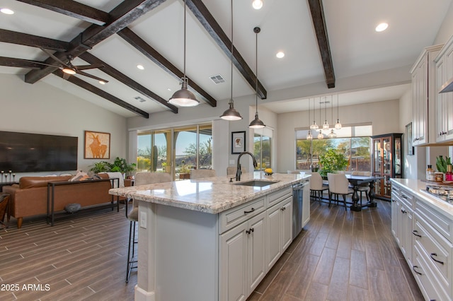 kitchen featuring light stone countertops, sink, a center island with sink, white cabinetry, and hanging light fixtures