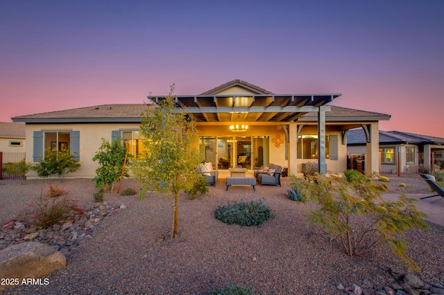 back house at dusk with outdoor lounge area and a patio